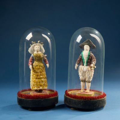 deux figurines miniatures représentant des personnes, placées sous un dôme en verre