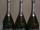 trois bouteilles de champagne posées sur une table l'une à côté de l'autre