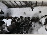une photo en noir et blanc montrant un groupe de personnes assises à une table