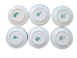 six white plates with green writing on them sitting on top of each other