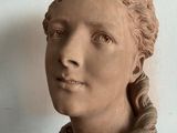a statue of a woman with braid hair in front of a picture frame