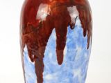 a blue and brown vase sitting on a white surface