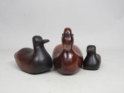trois petits canards en bois assis les uns à côté des autres sur une surface blanche