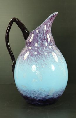 un pichet en verre violet et bleu posé sur une table