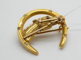 un gros plan d'une broche en or sertie de diamants sur un fond blanc