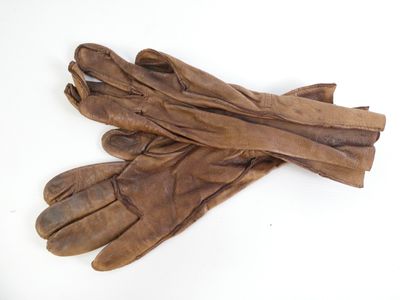 une paire de gants en cuir marron posée sur une surface blanche