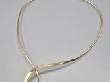 a gold plated necklace with a curved design on it