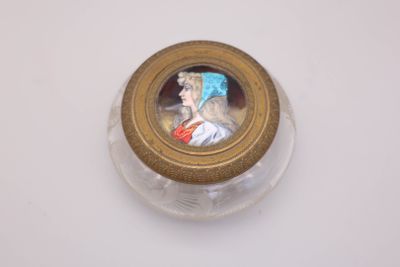 a small glass jar with a picture of a woman on it