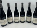 six bottles of wine are lined up in a row on a table