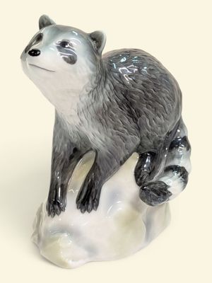 une figurine représentant un raton laveur assis sur un rocher