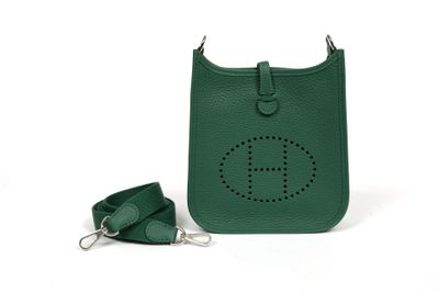 green leather handbag with keychain and strap on a white background