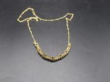 a gold necklace with small beads on a black surface