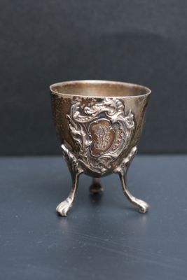 une coupe ancienne en argent posée sur un socle, sur une table