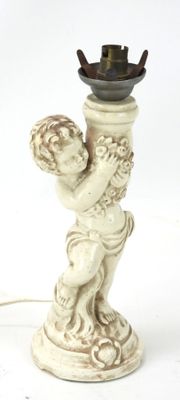 une petite statue représentant un garçon tenant une bougie, posée sur une table