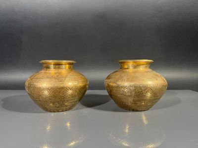 deux vases en or posés l'un à côté de l'autre sur une table