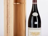 La bouteille de vin se trouve à côté de la boîte en bois, sur la table.