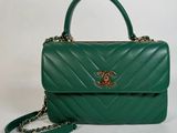 a green handbag with a chain strap and a gold clasp