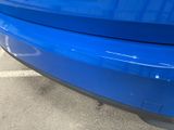 a close up of a blue car parked in a parking lot
