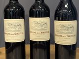 trois bouteilles de vin sont alignées sur une table en bois