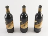three bottles of wine sitting next to each other on a white surface