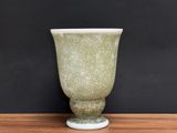 un vase vert posé sur une table sur fond noir