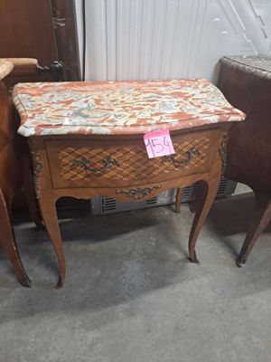 une petite table avec un tiroir, posée à côté d'une chaise