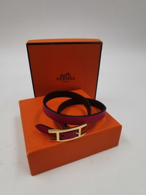 une ceinture violette et orange avec une boucle dorée, dans une boîte