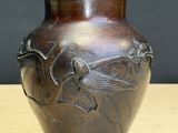 a brown vase with a bird on it sitting on a table