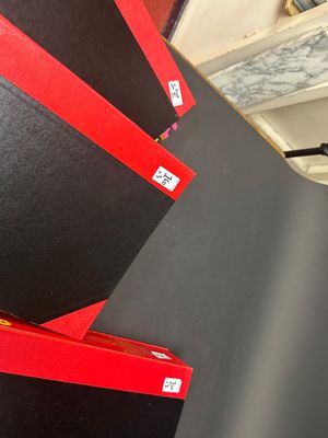 trois livres rouges et noirs posés sur une étagère dans une pièce