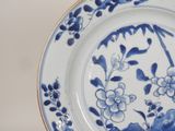 a blue and white plate with flowers and leaves on it