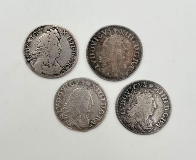 quatre pièces d'argent de tailles et de formes différentes sur une surface blanche