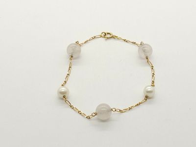 a close up of a bracelet with pearls on a white background