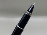 a black pen with a silver tip sitting on a white surface