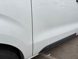 the side view of a white van parked in a parking lot