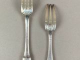 two forks and a spoon sitting on a table