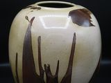 un vase marron et blanc posé sur une surface noire