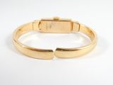 a close up of a gold bracelet on a white surface