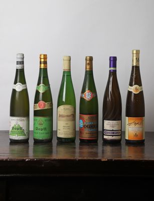 Des bouteilles de vin sont alignées sur une table devant un mur blanc.