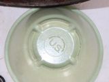 a green bowl sitting on top of a table next to a pair of scissors