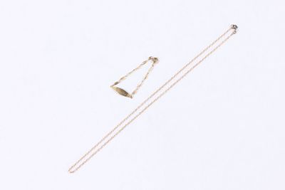 two gold necklaces and a pair of earrings on a white surface