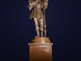 a bronze statue of a man holding a cross on top of a pedestal