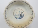 bol en porcelaine bleue et blanche représentant un homme dans un bateau sur l'eau