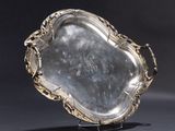 a silver tray with a handle on a stand on a black surface
