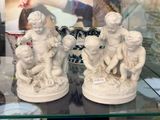 trois statues d'enfants assis sur une étagère en verre