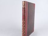un vieux livre à la couverture rouge posé sur une surface blanche
