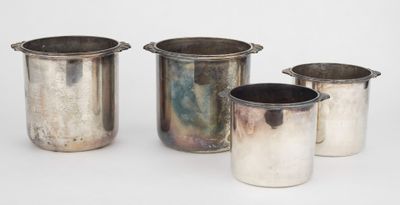 three silver vases and a silver cup on a white surface