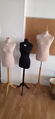 three mannequins in a room with a cork board on the wall