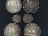 six pièces d'argent de tailles et de formes différentes sur un fond noir