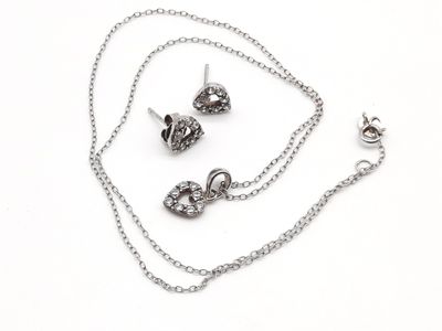 un ensemble composé d'un collier et de boucles d'oreilles posé sur une surface blanche