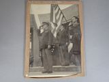 an old photo of two men in uniform standing next to an american flag